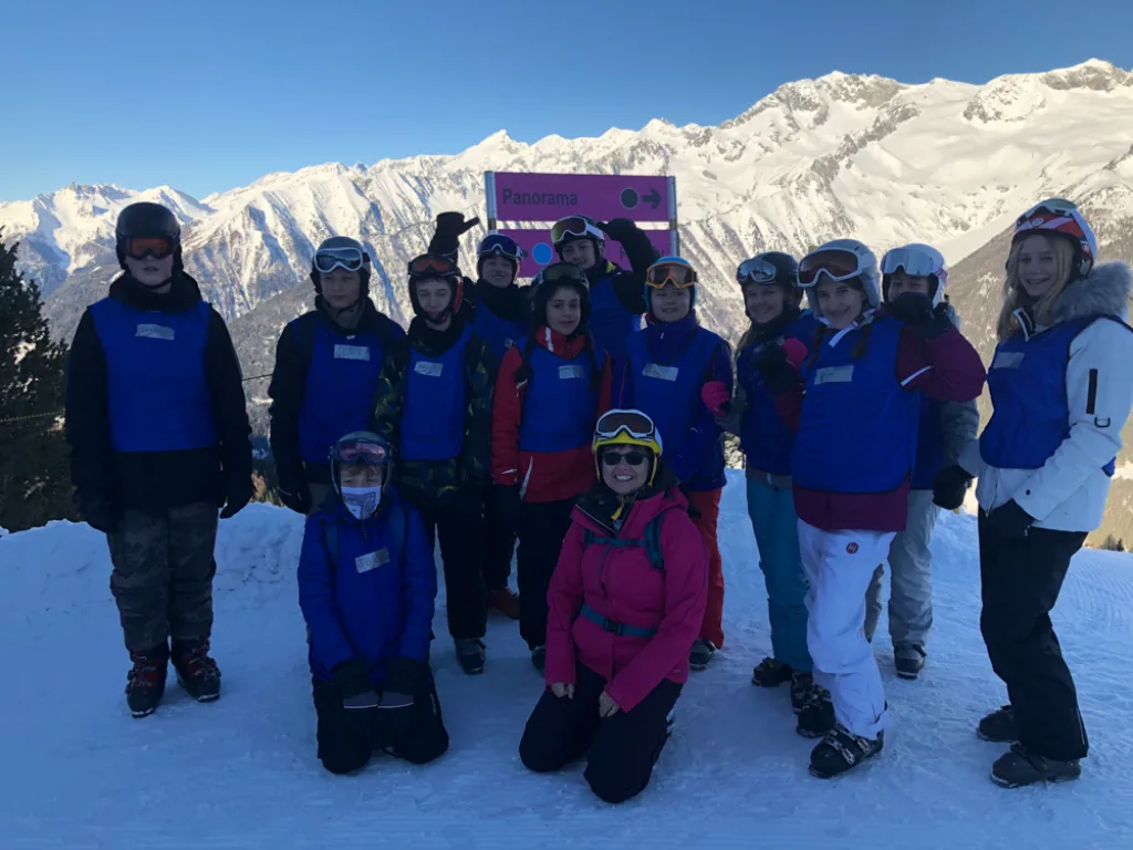 Skigruppe posiert vor der verschneiten Bergkette.